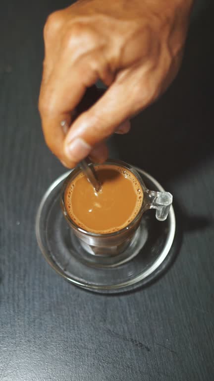 a cup of coffee milk stirred in a white glass with biscuits