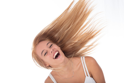 Joyful young woman laughing, her hair dynamically swept in the air, spirited expression