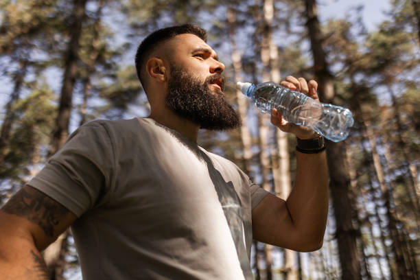 istock Young Athlete Jogging Through Nature's Pathways Taking a Break Hydrating 2148300120