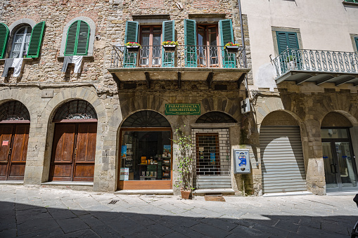 Lucignano, Italy - 23 of May 2022: Walking streets of small historic town Lucignano. View of old pharmacy facade