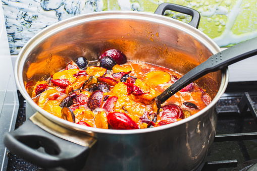 Sliced plum berries are boiled in a large saucepan. Making fruit jam, preserving and preparing for the winter.