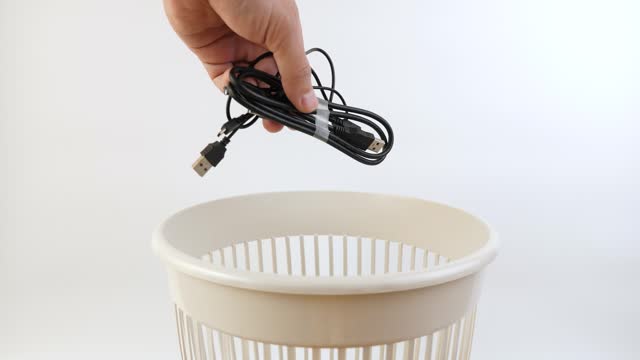 Old computer cables are thrown into the trash can. Disposal of household waste.
