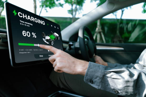 istock Electric car driver checks battery charging status app screen in car innards 2148302203