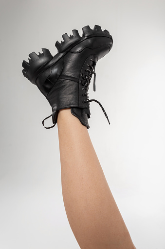 woman in black leather shoes from the new collection on a white background. girl's leg in fashionable vintage leather shoes fall-winter 2021.