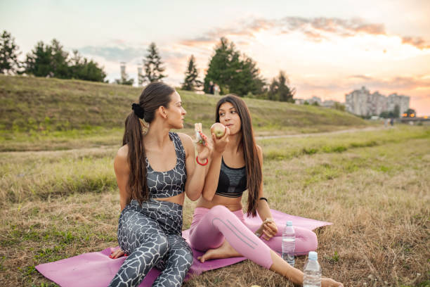 istock Two fit female friends eating snacks while exercising together in nature 2148303114