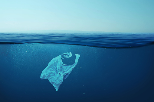 Creative background, plastic bag floating in the ocean, bag in the water. Concept of environmental pollution, non-decomposable plastic, increased debris in the world's oceans. Plastic pollution in sea