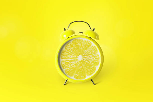 istock Creative alarm clock citrus fruit lemon on yellow background. Time for vitamin C, concept 2148303264