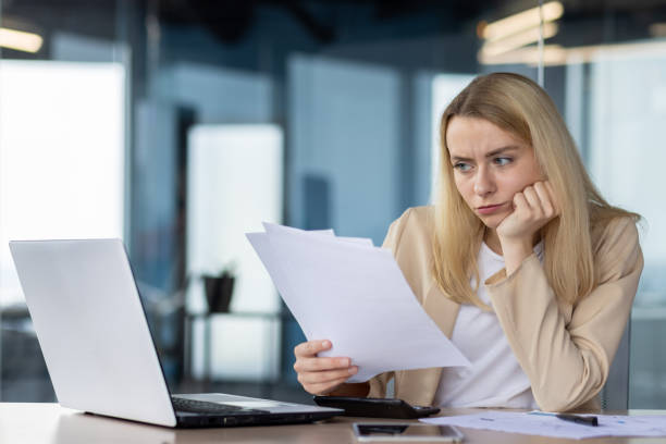 istock Young professional woman reviewing documents at her desk 2148303463