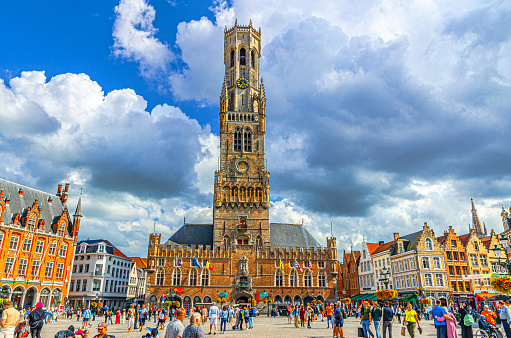 Bruges, Belgium, July 5, 2023: Belfry of Bruges Belfort van Brugge bell tower medieval building Scheldt Gothic architecture style and people tourists on Markt Market square in Brugge old town