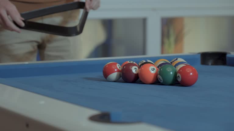 Close-ups of the hands of a man placing the billiard balls with the triangle that holds the balls to put them away before breaking the game with the cue