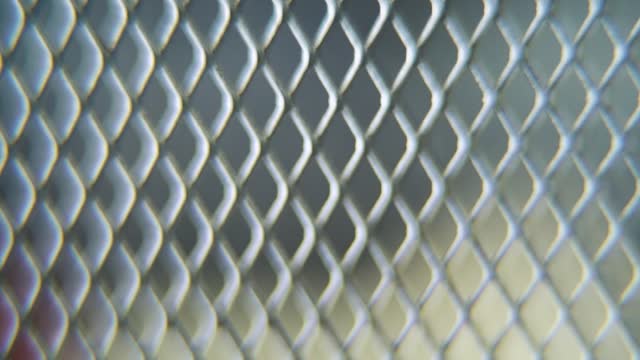 A hyper macro shot of a metal grid, steel pattern, iron industrial texture, aluminum material, super slow motion, Full HD 120 fps, smooth zoom out movement, blurry Depth Of Field