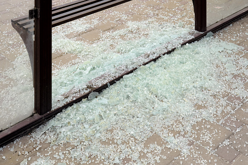 Close-up of a lot of broken glass at a public transport stop. An act of vandalism and riots in the city.