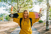 portrait of teenage girl with longboard on shoulders