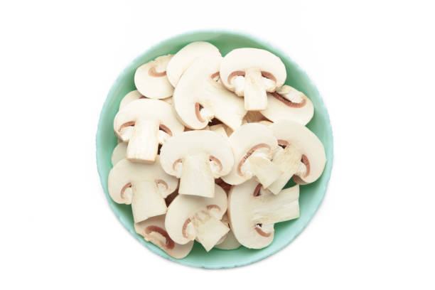istock Fresh white champignon mushrooms on mint plate isolated on white background. 2148304922