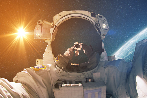 Space man makes selfie photo in outer space with the sun and planet earth. Astronaut photographer travels and takes photos in deep space. Travel concept