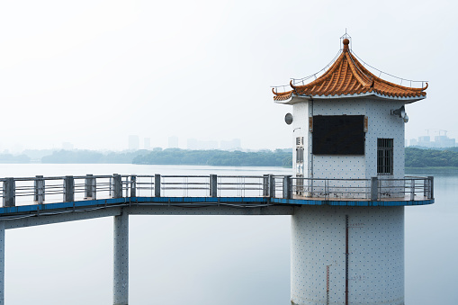 Nestled within the picturesque Songhu Misty Area of Songshan Lake in Dongguan, a collection of charming structures stands in harmony with the natural surroundings. Among them, an observation tower rises tall, offering visitors a panoramic view of the tranquil lake and its environs. Nearby, a lighthouse casts its watchful gaze across the water, guiding vessels safely through the gentle waves.

A water tower, its intricate design a testament to architectural ingenuity, stands as a beacon of functionality and beauty. Clustered around these larger structures are quaint, cozy houses that exude a sense of warmth and homeliness. This harmonious blend of man-made marvels and nature's splendor creates a captivating ambiance.

The lake itself is a living canvas, with fish darting beneath the surface, leaving behind trails of ripples that dance across the water's glassy expanse. The gentle lapping of waves against the shore adds a soothing rhythm to the scene, providing a serene backdrop to the architectural wonders that grace its banks.

As the sun's golden rays filter through the verdant canopy of the surrounding forests, dappled light plays across the structures, casting ever-changing patterns and shadows. The interplay of light and shadow, water and stone, creates a dynamic and visually stunning tableau that captures the essence of this tranquil oasis within the heart of Dongguan.