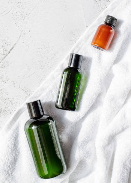 istock Three bottles with spa products, a white bath towel are on a gray background. 2148310058