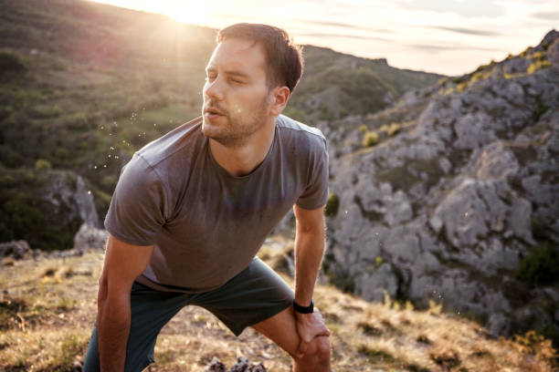 istock Exhausted young athletic man taking a break while running at the mountain 2148310169