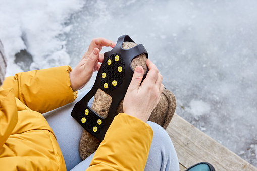 Wearing on studded overshoes on felt boots to improve traction on icy surfaces and prevent slipping.