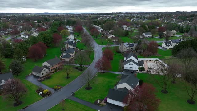Upper Class Neighborhood in Suburb of USA during spring season. Rainy day with clouds at sky. Luxury large single Family houses in residential area. Aerial birds eye shot.
