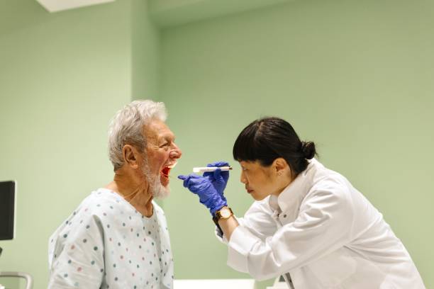 Doctor looking in patient’s mouth using a tongue depressor.