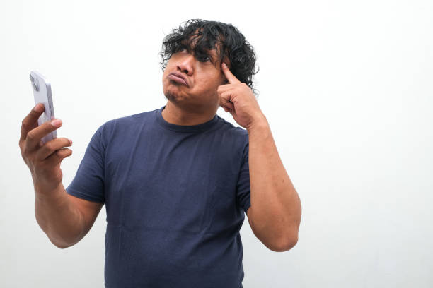 gesture of an Asian man thinking while holding a mobile phone