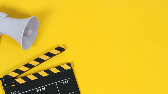 Clapper board or movie slate and megaphone on yellow background.