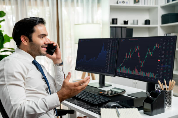 istock Trader calling to consultant or partner with two stock exchange screen. Surmise. 2148314860
