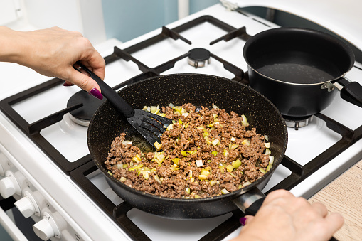 housewife frying minced meat with onions in a frying pan. frying minced meat. . High quality photo