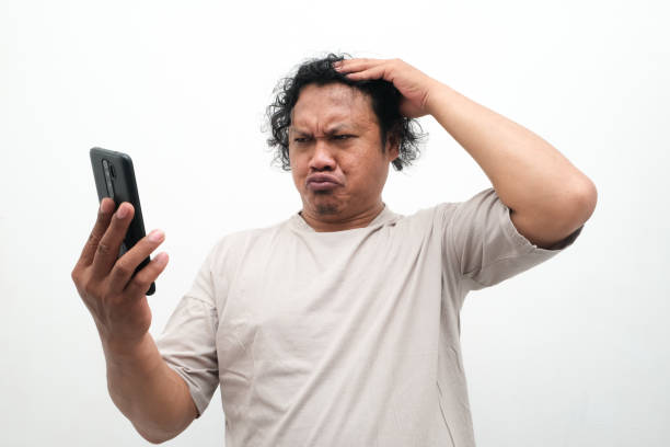 istock Adult Asian man looking to his phone with sad expression 2148317571