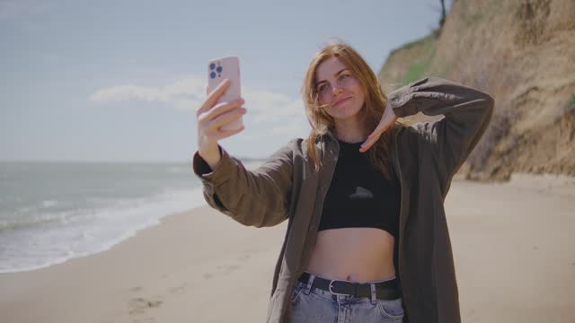 beautiful red-haired young woman takes a selfie on a deserted tropical beach near the ocean or sea