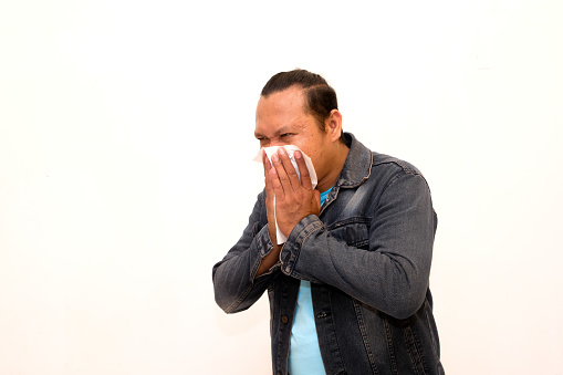 portrait of man in black jacket coughing covering his mouth with tissue isolated on white background
