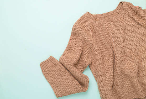 istock Beige knitted sweater on color background, top view 2148320343