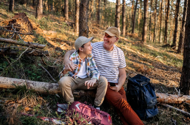 istock Father and son relaxing in nature in the spring sitting on tree log 2148321007