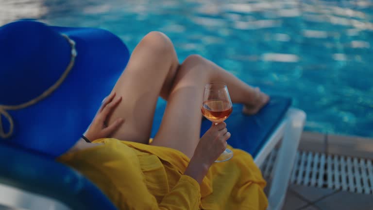 Woman in blue hat is relaxing near the pool.