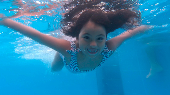 Little girl swimming in the pool, underwater view. 2.7K resolution video