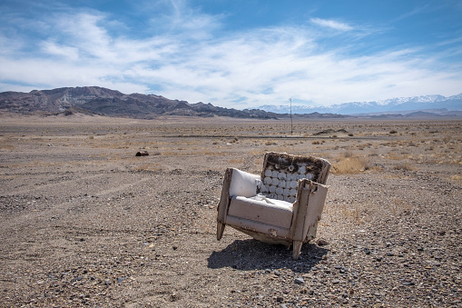 An empty, abandoned chair on an alluvial plain in the Great Basin Desert of Nevada, with mountain ranges in the background.
