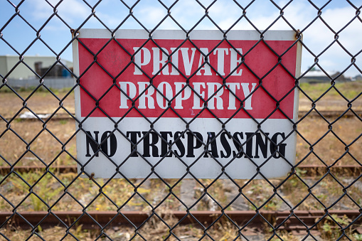 Private property sign attached to the inside of a chain link fence.