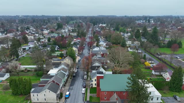 Rainy and clouds day in small american town with colorful trees and houses. Residential area with homes and garden in USA. Aerial lateral wide shot.