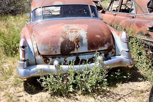 Vintage car abandoned and rusting away in rural countryside.