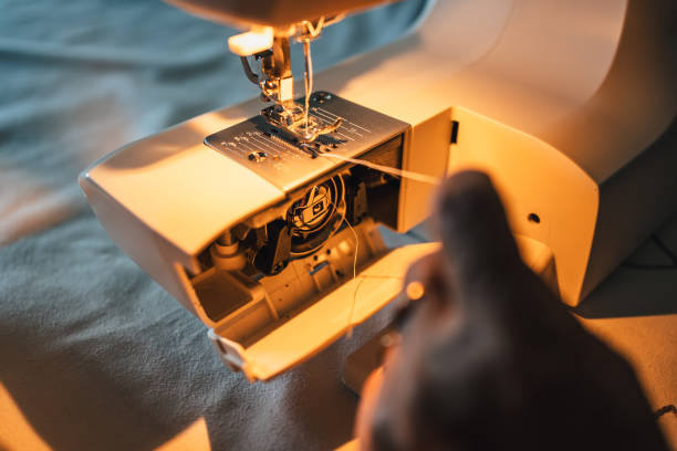 istock detail of woman's hand preparing sewing machine with thread 2148325347