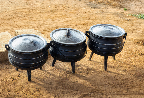 africa three cooking pots outside in the yard cooking meat the traditional way