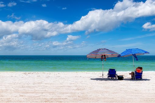 Sunny beach with colorful umbrella and beach chairs in white sand tropical beach