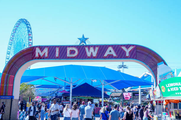 Dallas, TX, USA - October 20, 2023: The Midway at the State Fair of Texas with a crowd of people beneath the sign and the Texas Star Ferris wheel in the background