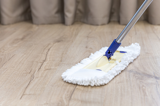 Modern white mop cleaning wooden floor from dust