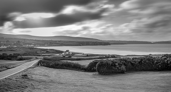 View from hill of cloudy beach scenery in black and white