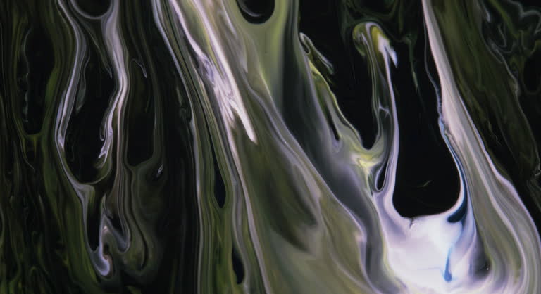 Moving streams of blue, green,white paint on a dark black abstract background, screensaver. Liquid abstraction.