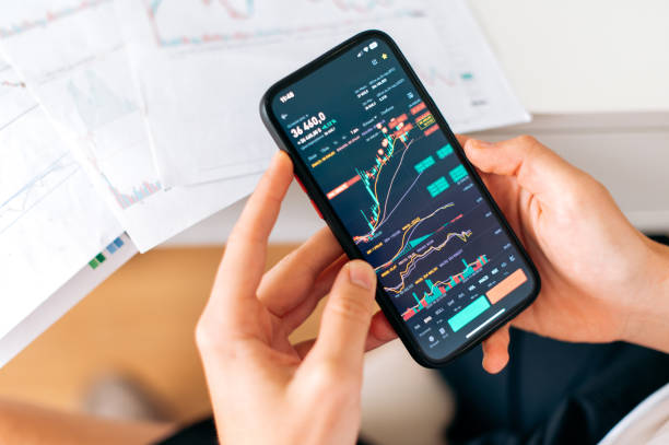 istock Close-up of a smartphone in male hands, with trading data index chart graph on the screen, mobile phone app analytics for cryptocurrency market. Online trading 2148329113