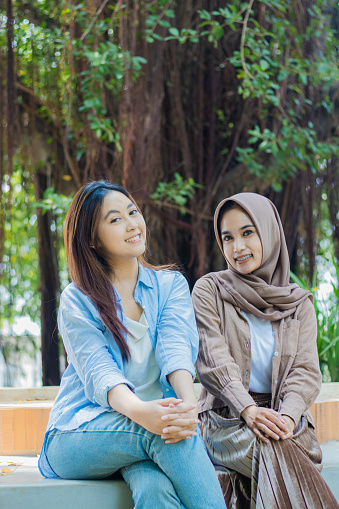 two happy Asian women friendship long time no see looking at the camera in the campus park. female students for education, promotion and lifestyle concepts