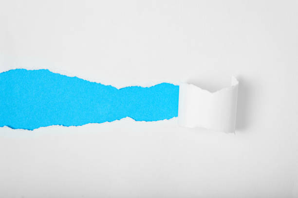 istock Torn white paper revealing blue background. Space for text. 2148329901